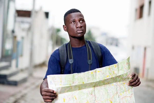 Молодой человек турист с картой на улице — стоковое фото