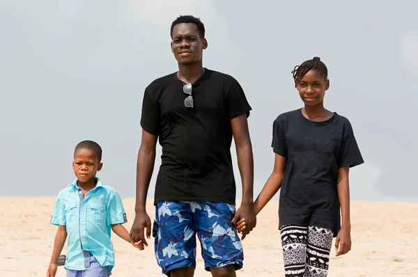 Een jonge man en zijn kinderen op het strand. — Stockfoto
