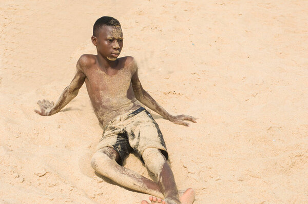 young teenager sitting in the sand.