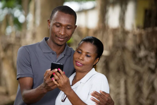 Smiling couple with mobile phone outside — Stock Photo, Image