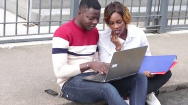 dizüstü bilgisayar gülerek el çırparak araştırma yapan derslerden sonra açık havada oturan öğrenciler.