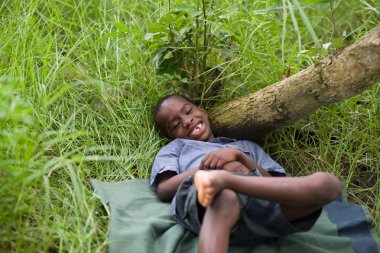 Çimenlerin üzerinde yatan mutlu küçük çocuk