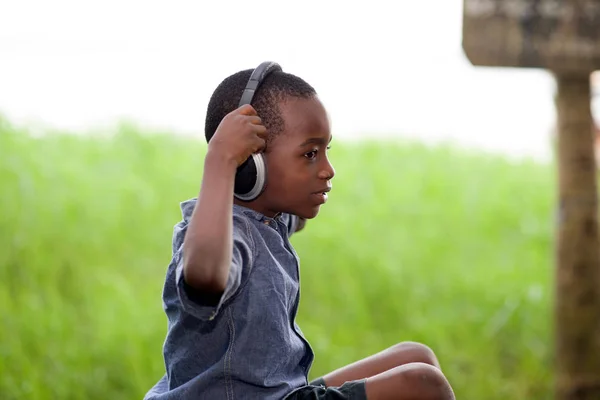 Niño sentado y escuchando música con auriculares — Foto de Stock