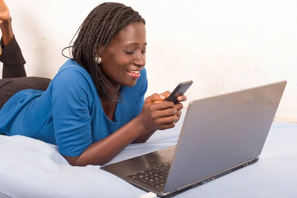 Mulher falando no telefone na cama na frente de um laptop . — Fotografia de Stock
