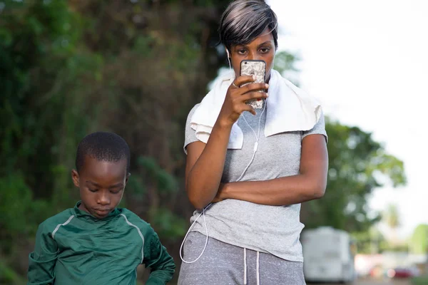 Mãe olha para o telefone enquanto seu filho está brincando perto dela — Fotografia de Stock