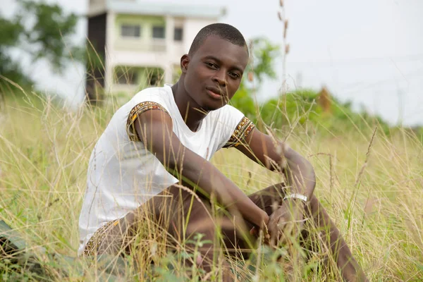 Porträt eines jungen Mannes, der im Gras sitzt — Stockfoto