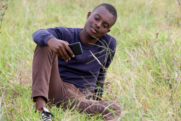 Joven en el parque utiliza un teléfono móvil — Foto de Stock