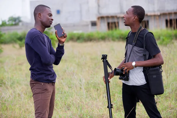 Dois jovens fotógrafos do sexo masculino conversando juntos na natureza . — Fotografia de Stock