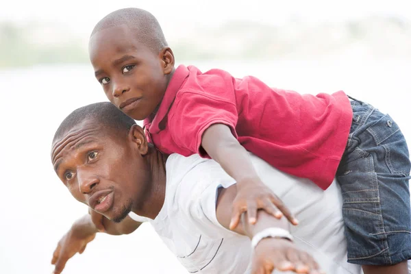 Mladý otec nesoucí syna usmívající se na zádech — Stock fotografie