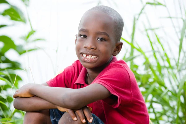 Kleine jongen glimlacht op de camera zittend in het gras — Stockfoto