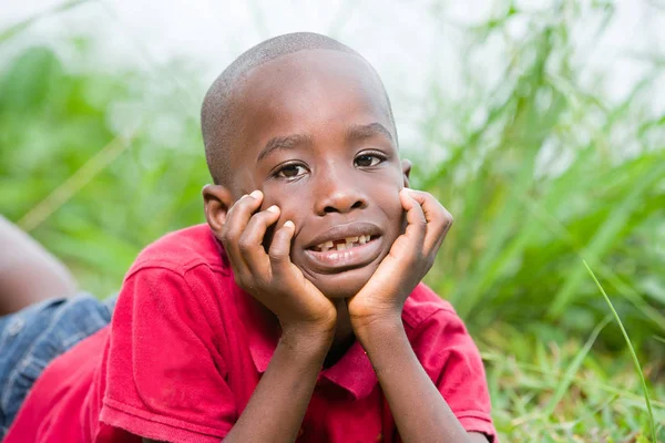 Retrato de lindo niño acostado sobre hierbas verdes frescas . — Foto de Stock