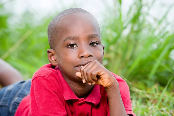 Retrato de lindo niño acostado sobre hierbas verdes frescas . — Foto de Stock