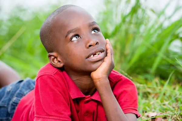 Retrato de lindo niño acostado sobre hierbas verdes frescas . — Foto de Stock