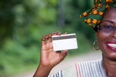 doğa arka plan üzerinde bir kredi kartı sunan Afrikalı kadının portresi