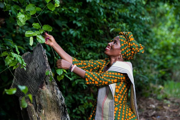 Afrikanerin geht in der Natur spazieren und hält eine Pflanze in der Hand — Stockfoto