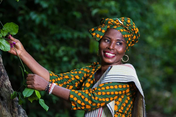 Mulher africana andando na natureza e segurando uma planta — Fotografia de Stock