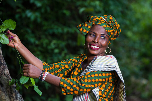 african woman walking in nature and holding a plant