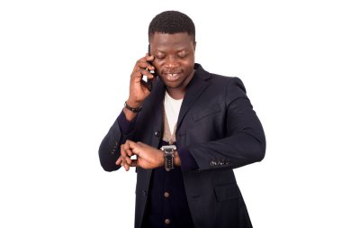 Genç işadamı saatini izlerken telefonda konuşuyor.