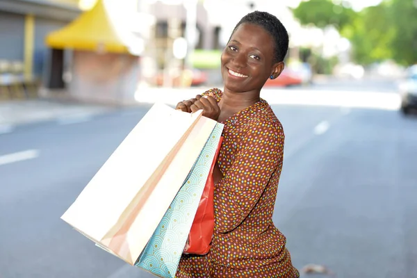 Счастливая женщина с сумками для покупок в городе — стоковое фото