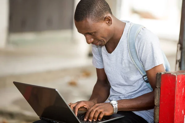 Młody student człowiek siedzi w mieście pracując z laptopem — Zdjęcie stockowe
