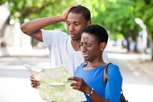 Young people standing on street looking at geographical map.