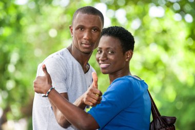 Genç insanlar başparmağında işaretle kameraya bakıp gülümsüyor..