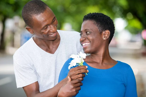 Junges glückliches Paar mit weißen Blumen auf der Außenseite — Stockfoto