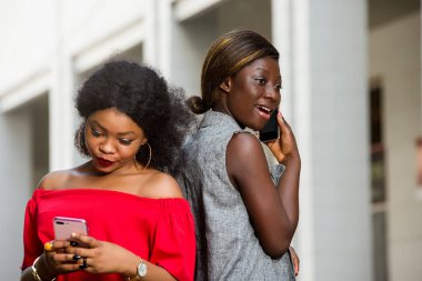 İki genç gülümseyen kadın dışarıda dikilip telefonda konuşuyorlar. Konsept iletişim ve gençlik.