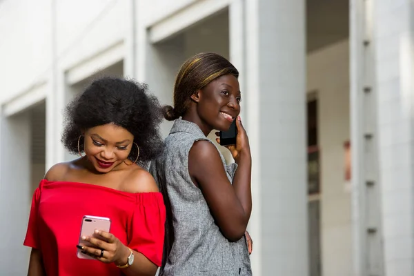Две Молодые Улыбающиеся Женщины Стоят Снаружи Разговаривают Телефону — стоковое фото