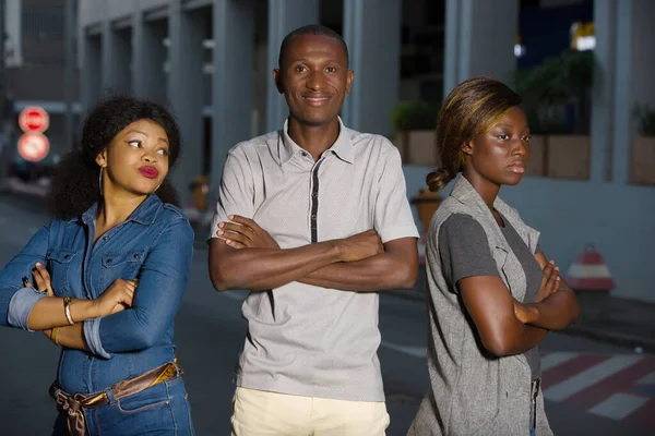 two jealous women are fighting a man.Divorce of a couple outdoors in the city man standing between two angry girlfriends is watching the camera