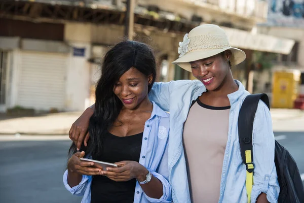 concept of travel, tourism and summer vacation - group of happy smiling friends with smart phone on city street background