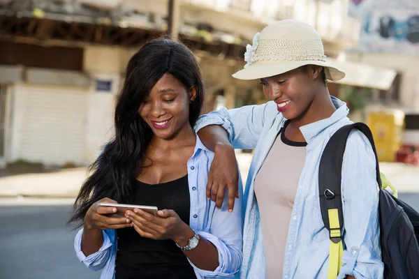 concept of travel, tourism and summer vacation - group of happy smiling friends with smart phone on city street background