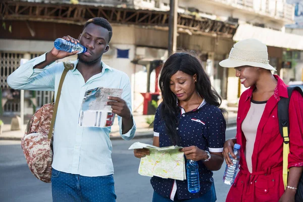 Grupo Jóvenes Turistas Pie Mirando Mapa Mientras Sonríen —  Fotos de Stock