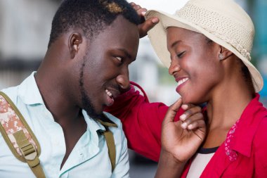 Dışarıda birbirine sarılmış gülümseyen iki genç turist..