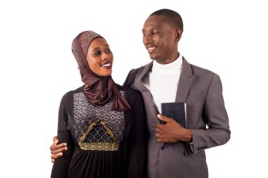 Beyaz arka planda ayakta durup gülümseyen iki dindar insanın portreleri..