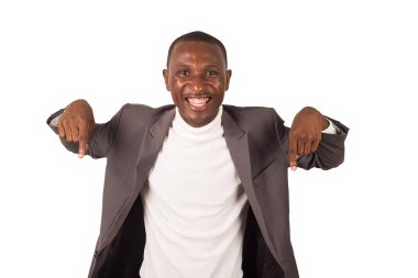 Beyaz arka planda duran genç adam parmaklarıyla hareket ederken kameraya gülümsüyor..