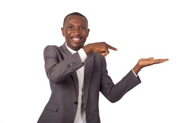 Beyaz arka planda duran takım elbiseli genç bir adamın portresi sol elinde bir şey gösteriyor..