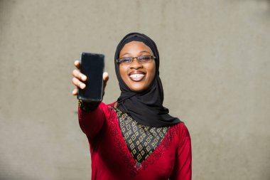 Gözlüklü genç Müslüman kadın cep telefonu kapısının güldüğünü görmüş..