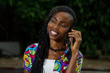 Güzel bir yağmurun altında dikilen Afrikalı kız gülümsüyor..