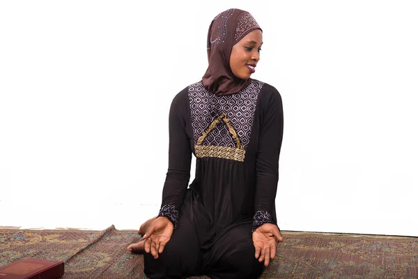 若いイスラム教徒の女性座っています長いドレス上のマットの祈りプロフィール笑顔を見て — ストック写真
