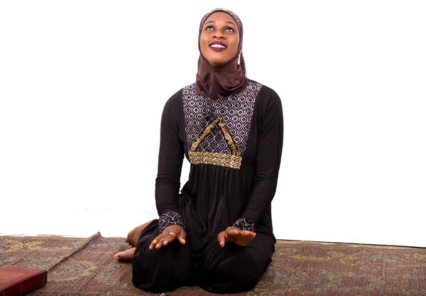 年轻的穆斯林妇女穿着长裙坐在垫子上 微笑着祈祷 — 图库照片