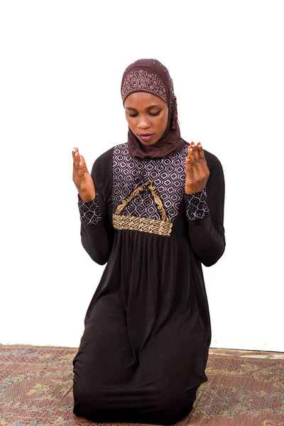 マットの上でひざまずいて祈る若いイスラム教徒の女性 — ストック写真