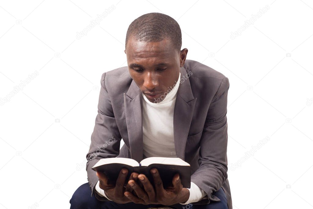 portrait of young pastor sitting and immersed in reading a Bible he holds in his hands.