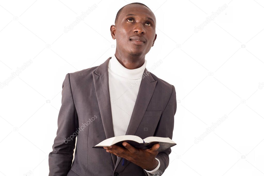 portrait of young pastor standing and reading a Bible in his hand.