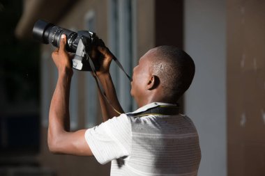 Genç fotoğrafçı dışarıda kamerasının ekranına bakıp gülümsüyor..