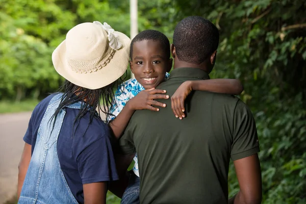 a family standing in a park and giving back to the camera.