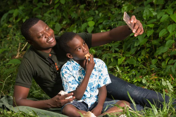 Genç Bir Aile Parkta Gülümserken Cep Telefonu Izliyor — Stok fotoğraf