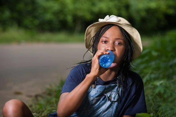 公園に座ってボトルで水を飲んでいる若い女性が — ストック写真