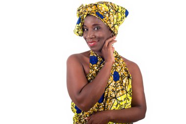 Genç Afrikalı bir kadın stüdyoda peştemalle duruyor ve profil kamerasına bakıp gülümsüyor..