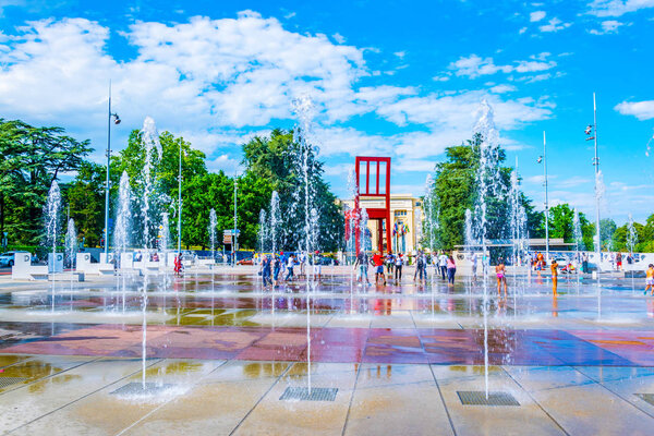 ЖЕНЕВА, ШВЕЙЦАРИЯ, 20 июля 2017 года: Туристы восхищаются скульптурой сломанного стула Даниэля Берста перед Дворцом Наций в Женеве, Свитцерлан
